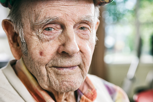 A close-up of a senior citizen man in an indoor setting.