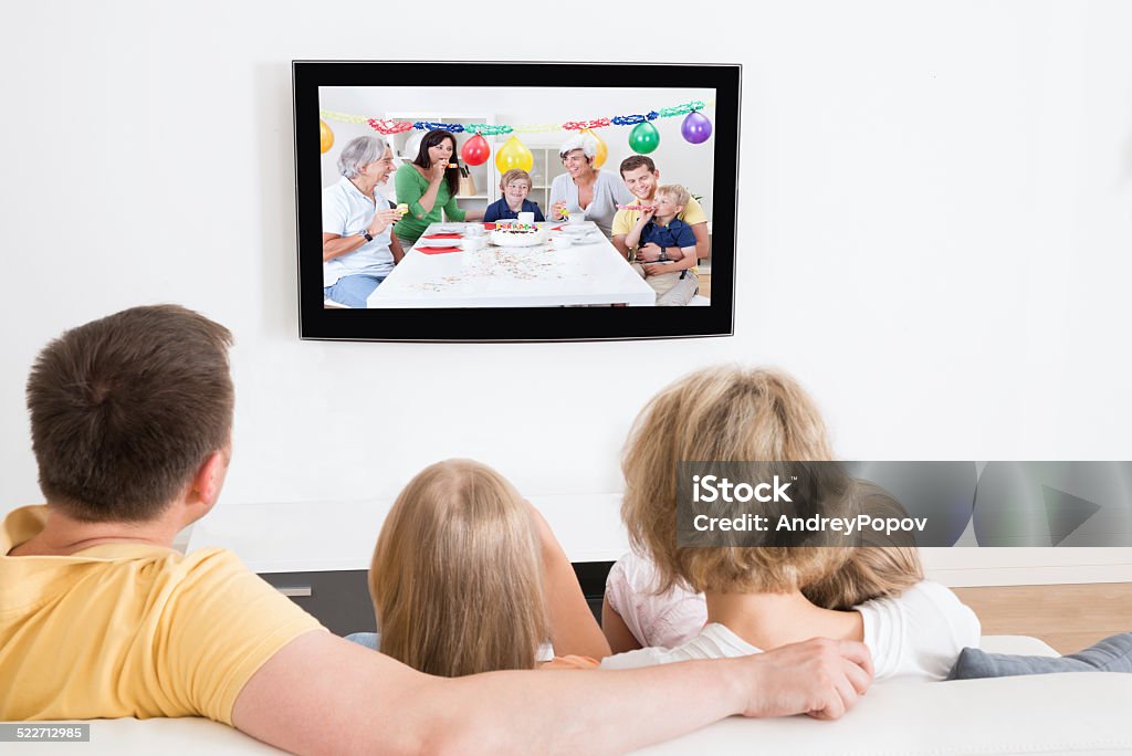 Young Family Watching TV Together Young Family Watching TV Together At Home Adult Stock Photo