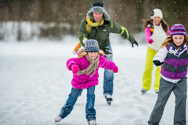 Family Ice-Skating on Pond A family ice-skating on a frozen pond on a snowy day. ice skating stock pictures, royalty-free photos & images
