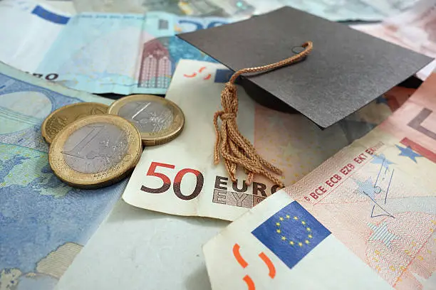 Euro notes and coins with mini graduation cap