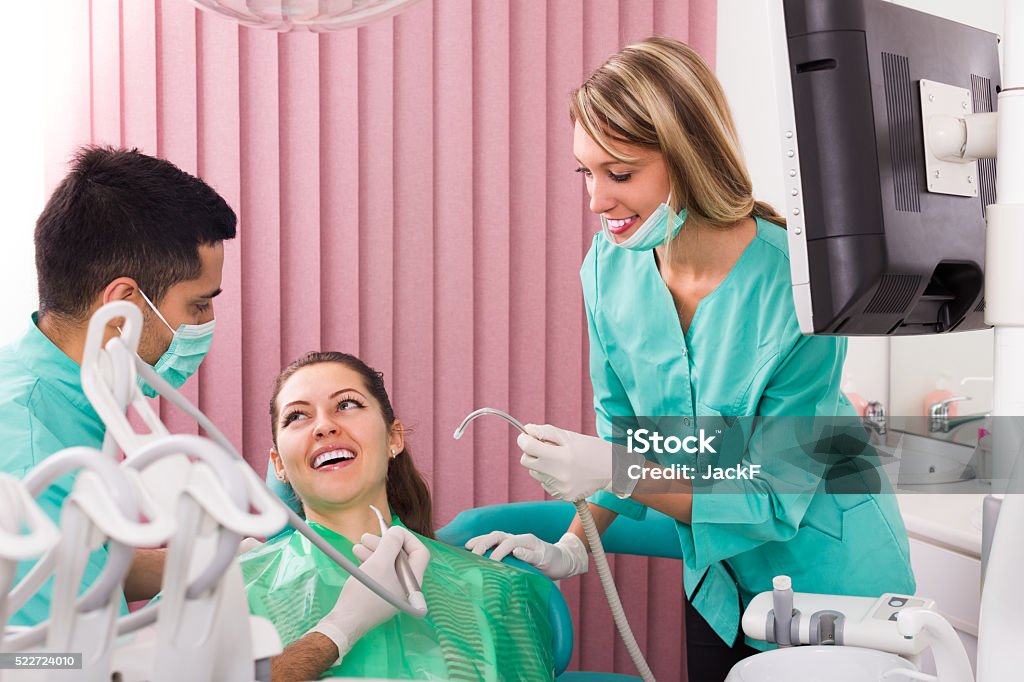 Happy patient at dental clinic Smiling young female patient and dentist with his assistant during check up at clinic 20-29 Years Stock Photo