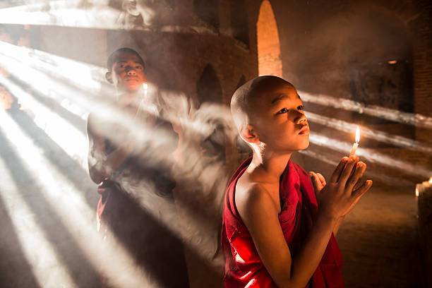 Young buddhist monks in Myanmar Two young buddhist monks praying inside the temple in Bagan, Myanmar bagan archaeological zone stock pictures, royalty-free photos & images