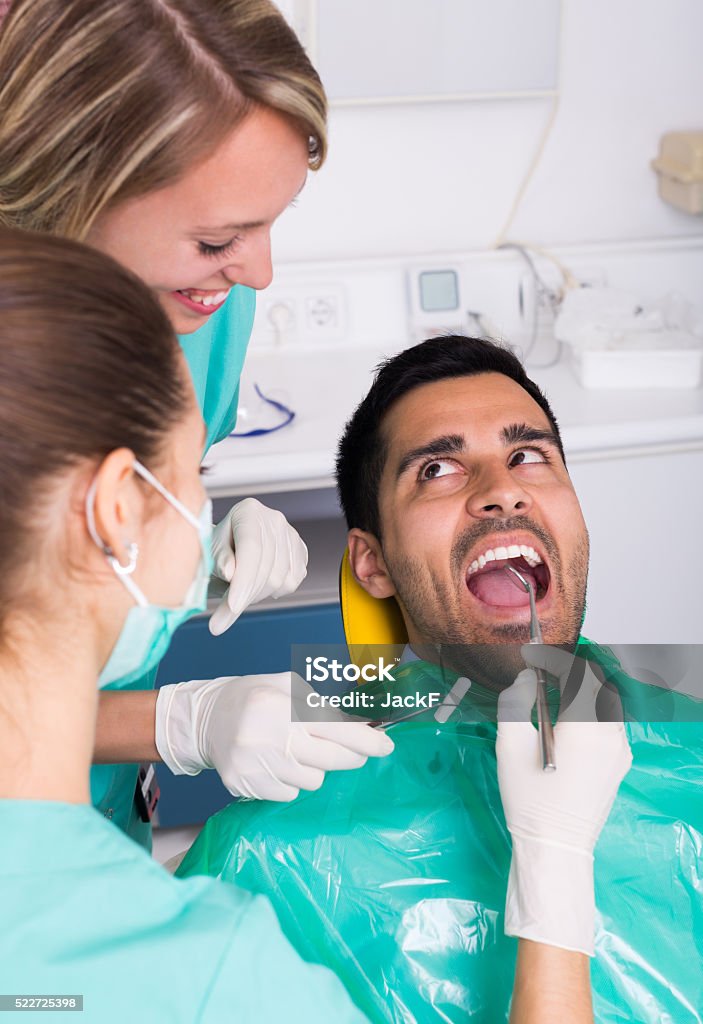 Patient at dental clinic Male patient and dentist with assistant during check up at dental clinic Assistance Stock Photo