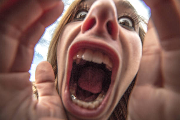 Young woman takes a selfie portrait making a face Young woman takes a selfie portrait making a face close-up to the camera. mouth open human face shouting screaming stock pictures, royalty-free photos & images