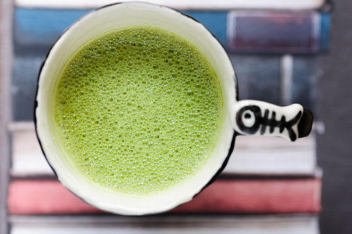 Fresh matcha latte tea on heap of books.