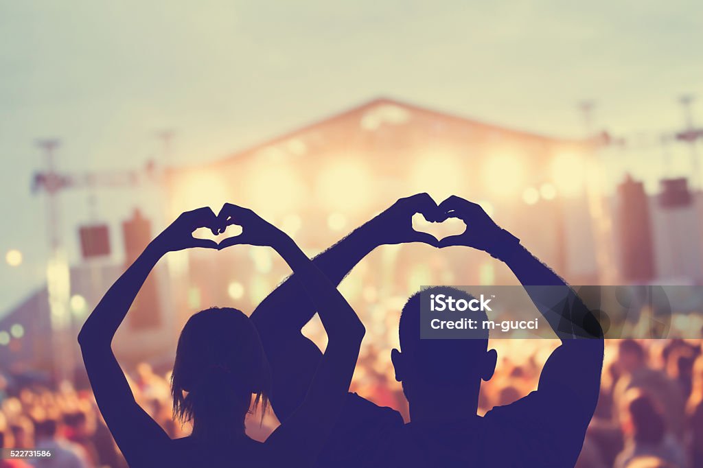 Couple making a heart-shape symbol for their favourite band. Music Festival Stock Photo