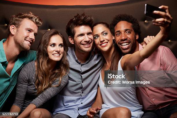 Happy Friends Taking Self Portrait At Nightclub Stock Photo - Download Image Now - Party - Social Event, Selfie, Sofa