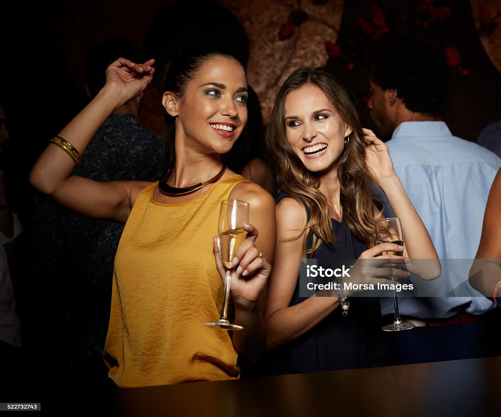 Cheerful female friends dancing in nightclub Cheerful female friends dancing while having champagne in nightclub Party - Social Event Stock Photo