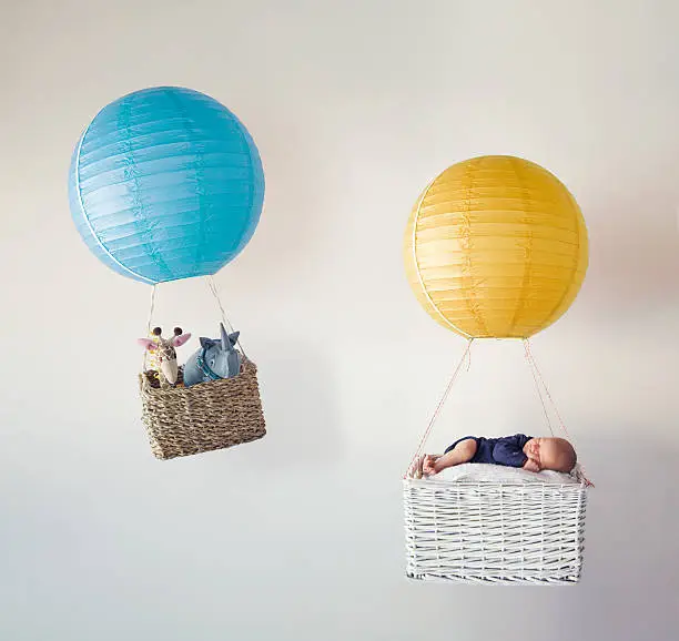 A newborn baby and his stuffed animal friends in two tiny air balloons