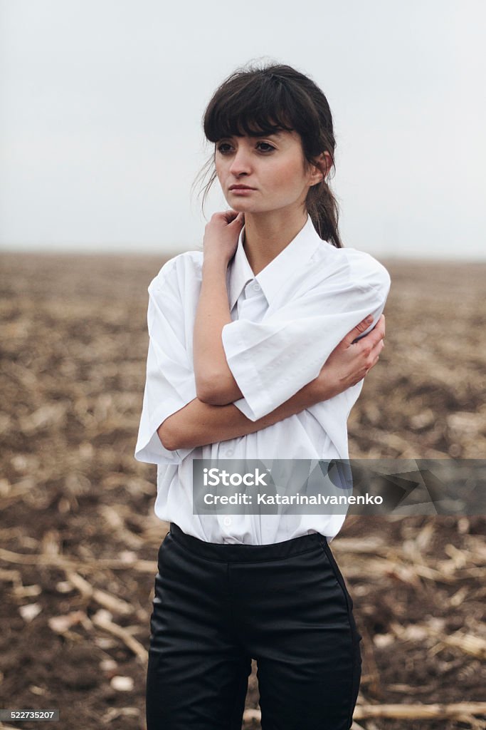 Girl in a white shirt standing in the field Girl in a white shirt standing in the empty field Adult Stock Photo