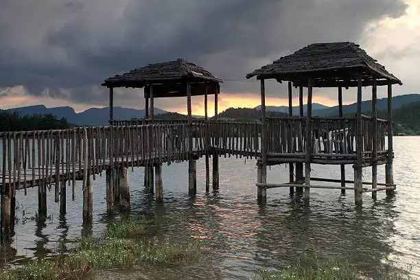 Wooden pier and gazebo on a lake at dusk.