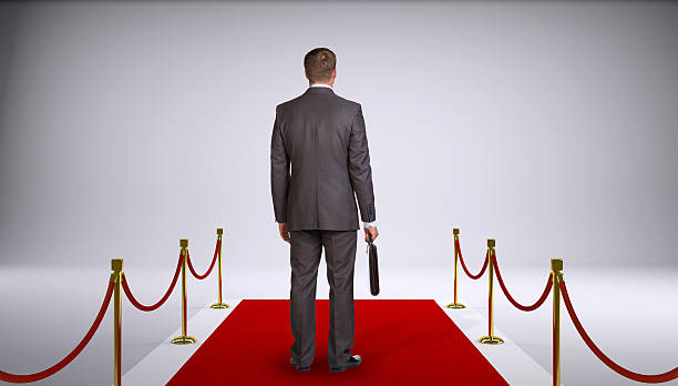 istock Businessman in suit holding briefcase and standing on red carpet. 522736441