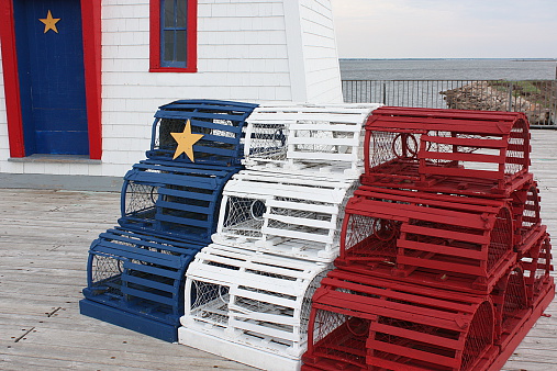 A set of lobster traps are stacked and painted in the colors of the Acadian flag in New Brunswick, Canada.