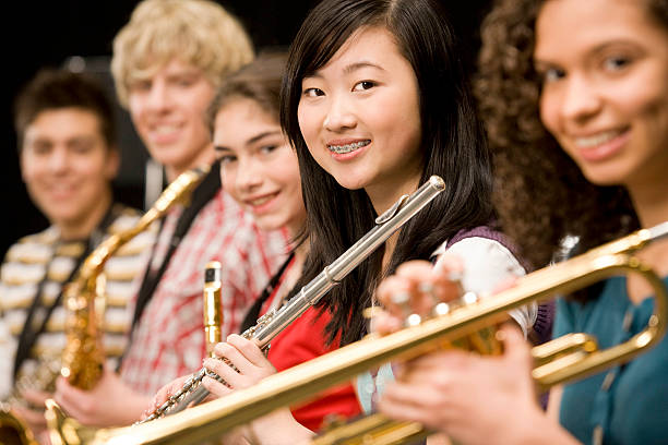 istock High-school girl playing flute with schoolmates 522737823