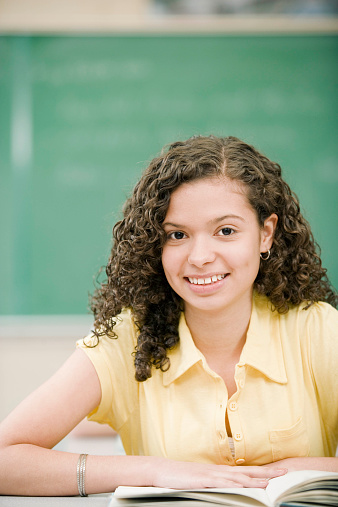 Teenage girl smiling with an open book on desk