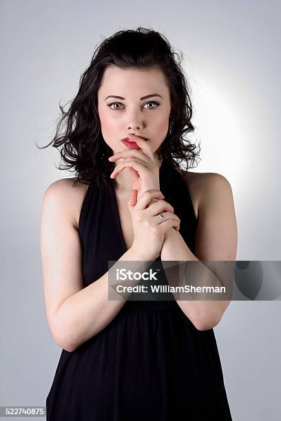 Brunette In A Black Dress Finger On Lip Stock Photo - Download Image Now - Adult, Adults Only, Artist's Model