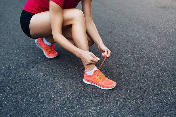istock Female runner lacing up her shoes on the trail 522740877