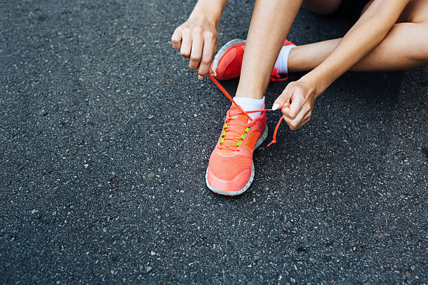 Lacing up before the jog Close-up of a runner lacing her shoes lace up stock pictures, royalty-free photos & images