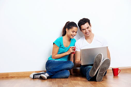 wireless laptop computer with couple sitting on floor in new empty apartment