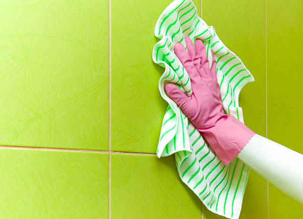 istock Hand in pink protective glove cleaning tiles with rag. 522746726