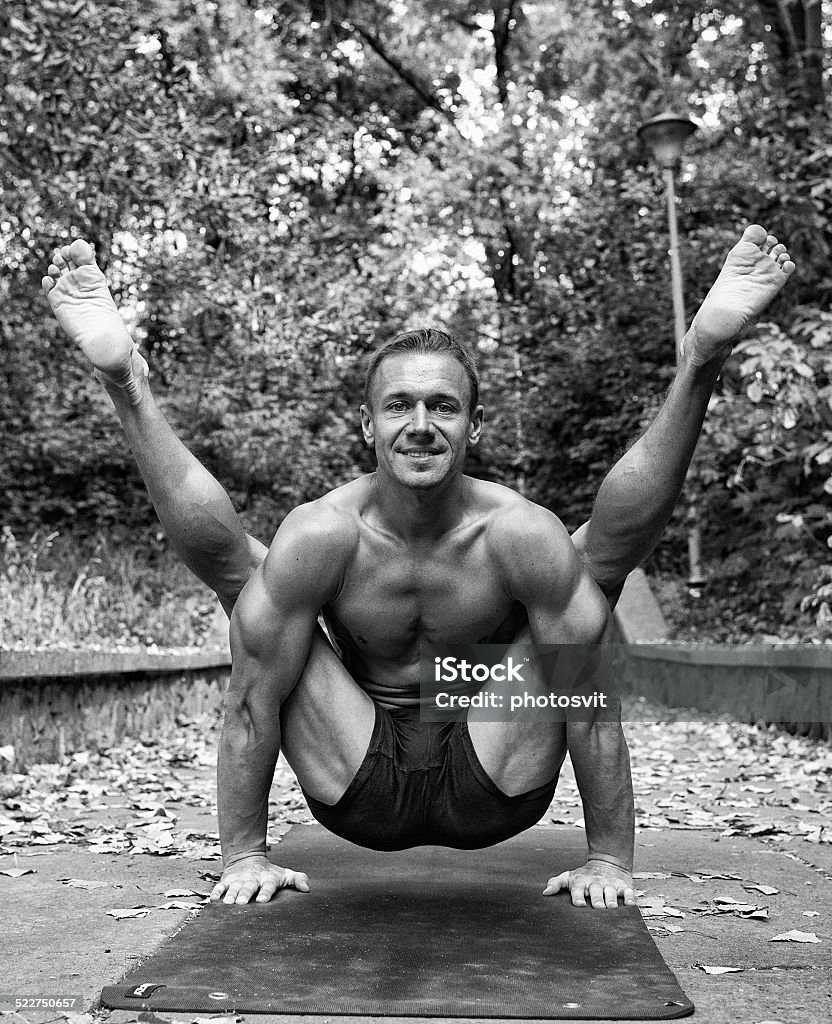 Athletic man doing yoga asanas in the park Athletic man doing yoga asanas in the park, on the hill. black and white, hdr Active Lifestyle Stock Photo