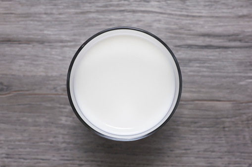 Glass of fresh milk on wooden table. Directly above view. Photo is taken with dslr camera in studio.