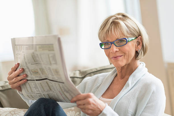 istock Woman Reading Newspaper While Relaxing On Sofa 522764605