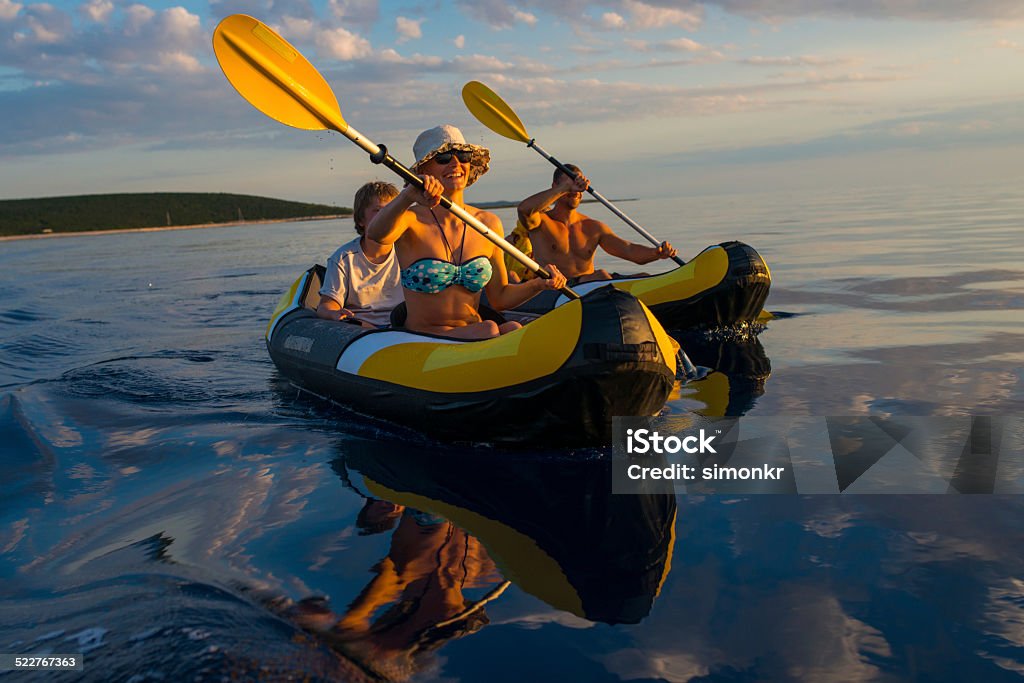 Family Having Fun Sea Kayaking Family enjoy sea kayaking in the late afternoon sun.   Active Lifestyle Stock Photo