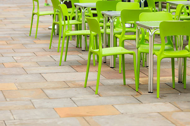 Brightly painted neon yellow metal patio chairs and table against a blue painted brick wall.