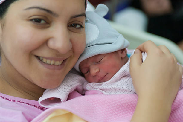 A newborn baby enters the world and mother holding newborn baby girl in the hospital.