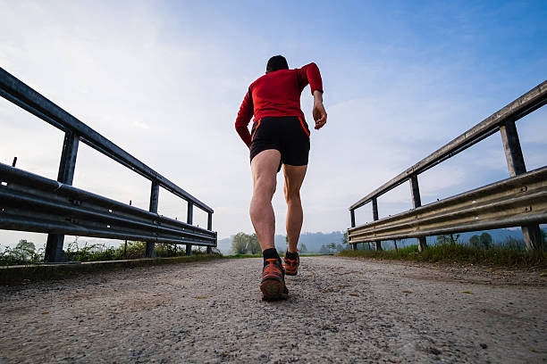 Man running in the country early in the morning A man running on a trail path early in the morning strada sterrata stock pictures, royalty-free photos & images