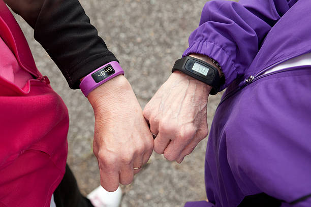 Wearable Fitness Technology Two ladies comparing their step counts on their wearable fitness watches. pedometer stock pictures, royalty-free photos & images