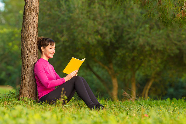 istock young woman reading book in the park 522779660