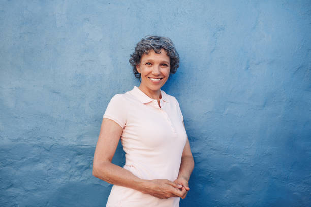 istock Smiling mature woman standing against blue background 522780078