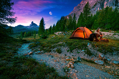 Mystical night landscape, in the foreground hike, campfire and tent