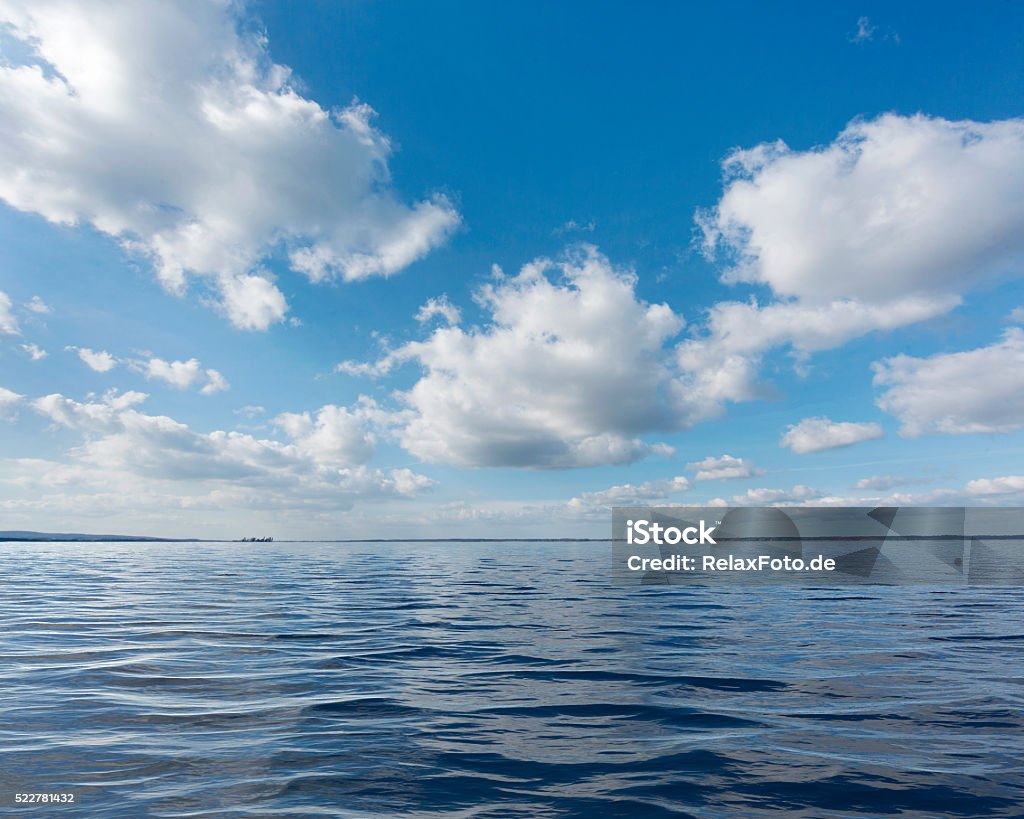 Majestic cloudscape over lake - blue sky white clouds Majestic cloudscape over lake. Exposure with extreme wide-angle lens. Maybe useful for backgrounds. Horizon Over Water Stock Photo