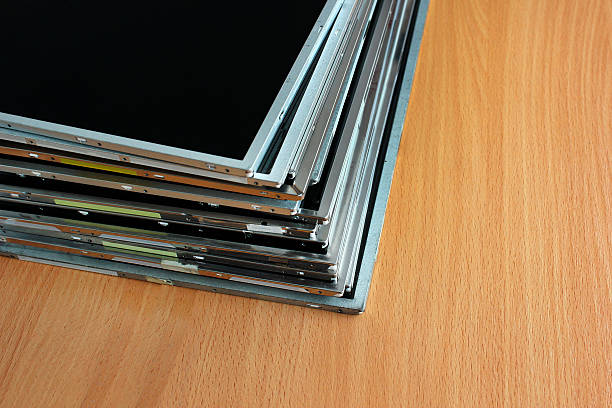 Stack of old lcd and tft panels on wooden table.