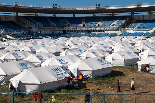 Athens, Greece - March 30, 2016: Two girls play volleyball surrounded by UNHCR tents, in the abandoned Athens olympic baseball stadium, today used as a refugee camp for refugees coming from Irak, Afghanistan and Syria.