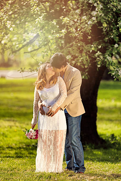 istock Expecting mom and dad kissing under flowering tree 522791042