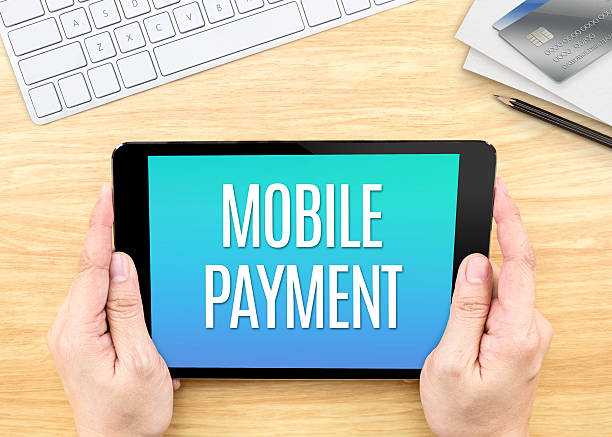 istock Hand holding tablet with Mobile payment word on wood table 522799262