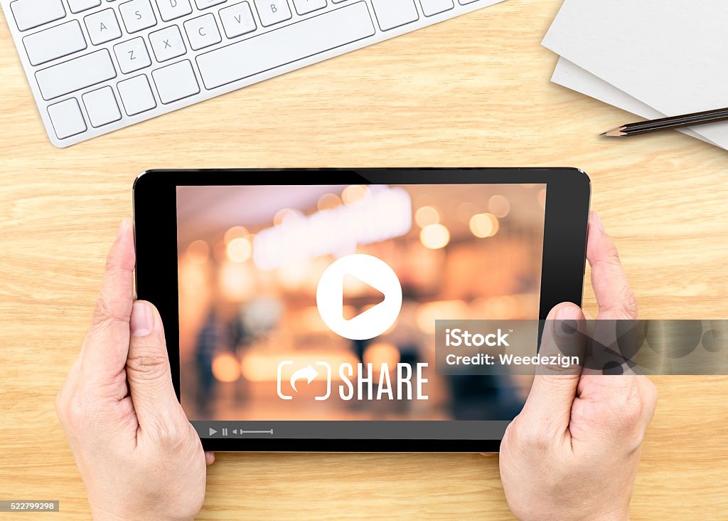 Hand holding tablet with Video sharing on screen on table Hand holding tablet with Video sharing on screen on wood table ,Internet marketing concept Advertisement Stock Photo
