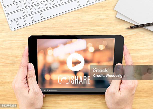 Hand Holding Tablet With Video Sharing On Screen On Table Stock Photo - Download Image Now
