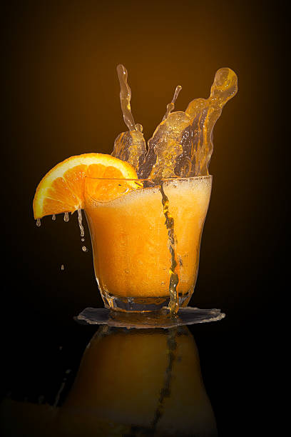 istock Orange flavoured soft drink splashing over the glass. 522800541