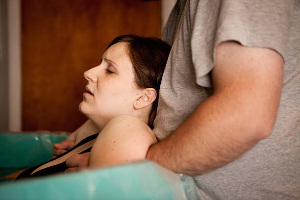 marido segurando esposa em casa-de-obra durante o parto dentro de água - labour room imagens e fotografias de stock