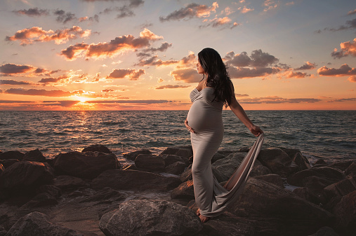 A beautiful maternity portrait taken at sunrise on a rocky beach in South Florida.