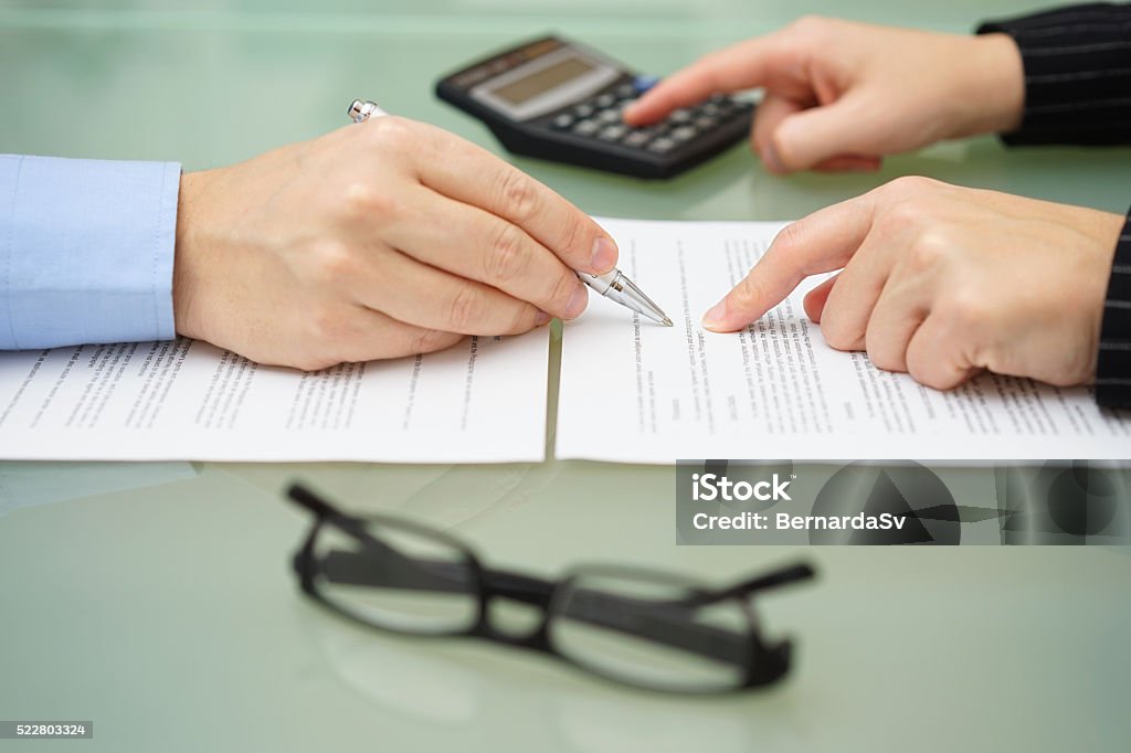 Mujer de negocios está examinando documentos con el consultor impositivo y cálculos - Foto de stock de Contrato libre de derechos
