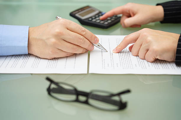 businesswoman is reviewing document with tax consultant and making calculations stock photo
