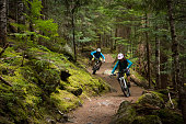 Couple mountain biking through a forest