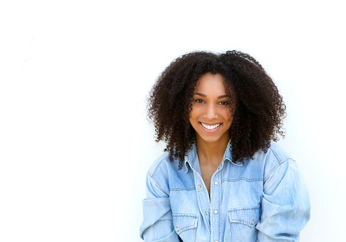 Close up portrait of an attractive young black woman with curly hair smiling on isolated white background