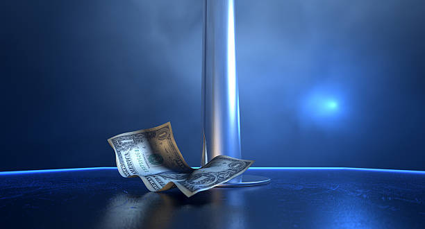 Stripper Tips On Stage An isolated stripper pole on a stage lit by a single spotlight with only one crumpled up one dollar bill tip on a stripclub background strip club stock pictures, royalty-free photos & images